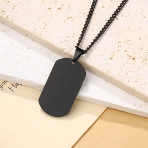 Flat lay of black rectangular military tag pendant necklace on a textured stone background