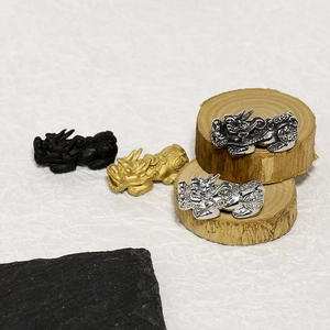 Detailed macro view of 18K gold plated and silver stainless steel Pixiu charms on wood