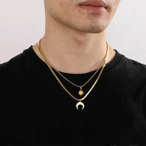 Gold double-layered necklace featuring sun and moon pendants on a sleek herringbone chain
