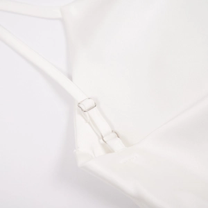 Gros plan sur les fines bretelles réglables et boucles argentées de la robe en satin blanc