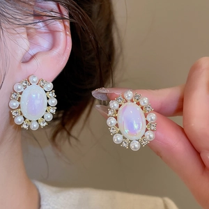 Detailed view of vintage gold stud earrings with oval moonstone and pearl accents