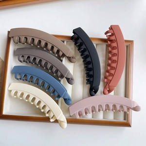 Set of six large matte banana hair clips in various colors displayed in a wooden jewelry box