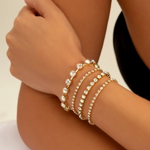 Close-up of four-piece gold bracelet set featuring rhinestones on a female wrist