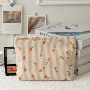 Macro shot of floral corduroy makeup bag texture with small orange fruit patterns