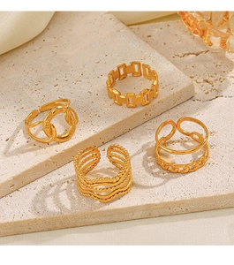Detailed view of four golden geometric stainless steel rings on a beige travertine surface