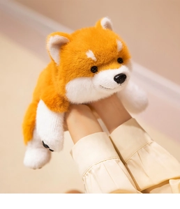 Close-up of hands holding a fluffy Shiba Inu plush toy with soft orange and white fur