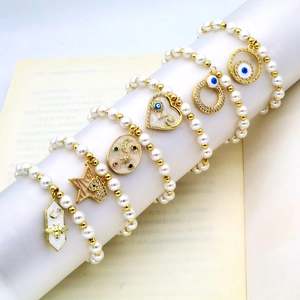 Detail von Perlenarmbändern mit goldenen Evil Eye-, Herz- und Stern-Mond-Anhängern auf Büchern
