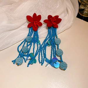 Detail of red flower earrings with long blue beaded tassels and iridescent sequins