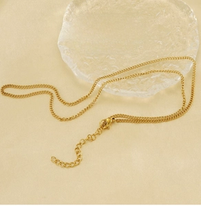 Close-up of golden stainless steel curb chain with lobster clasp and adjustable tail