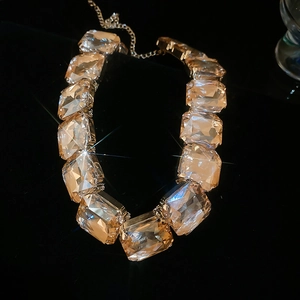 Macro detail of square cut crystal necklace with gold settings on reflective background