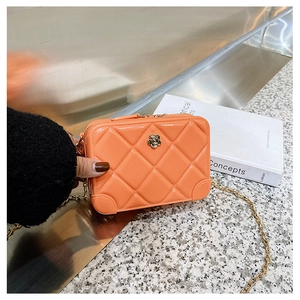 Detail of orange PVC jelly bag with quilted pattern and flower metal clasp on gold chain