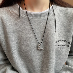 Macro detail of silver croissant pendant with textured folds on a black leather cord