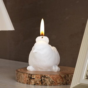 Detailed view of 3D bird scented candle with fine feather texture and lit flame