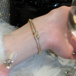 Detailed close-up of 18k gold plated bracelet featuring double rows of zircons and bow design