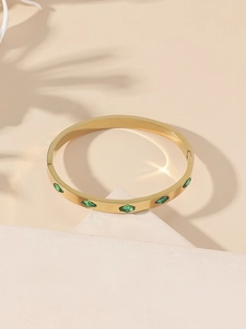 Detailed view of a gold-plated stainless steel bangle set with green rhombus-shaped crystals