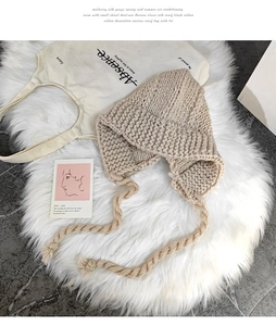 Détail d'un bonnet en grosse maille avec protège-oreilles, tresses et texture épaisse