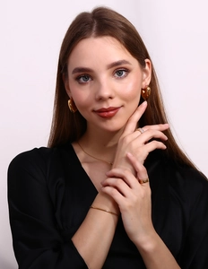 Detailed set of 18K gold plated heart earrings, sleek necklace, and layered rings on model
