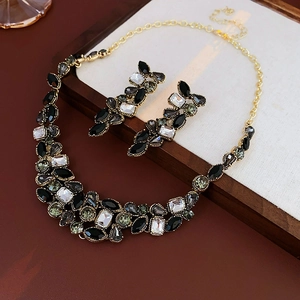 Détail de collier et boucles d'oreilles dorés vintage avec cristaux noirs et gris