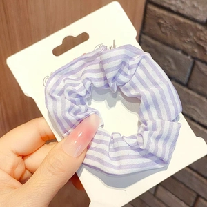 Detailed close-up of a purple and white striped fabric scrunchie on a white display card