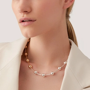Macro shot of two-tone gold and silver beaded choker necklace on model's neck