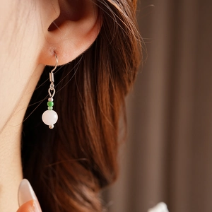 Close-up of a pink quartz and shell bead earring worn by a model in soft lighting