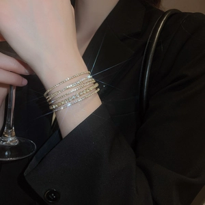 Close-up of elegant gold multi-layered tennis bracelets with sparkling zircon crystals