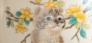 Macro detail of Ru ware ceramic tea cup with hand-painted cat and flower patterns