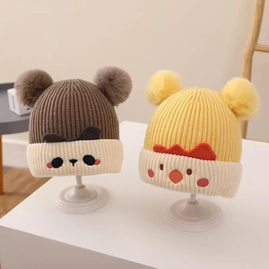 Close-up of baby winter hats with cute panda and chicken knit patterns and pom-poms