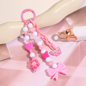 Détail d'un porte-clés rose avec nœud en résine, perles en forme de fleur et de cœur