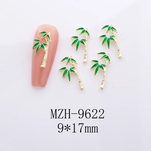 Detail of 9*17mm golden bamboo nail charms with green enamel on pink false nails
