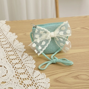 Détail du sac bandoulière en paille vert menthe avec nœud en dentelle et broderie