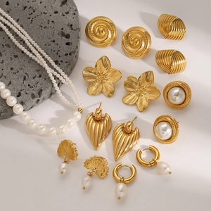 Close-up of gold vintage floral earrings and pearl necklace on a grey stone base