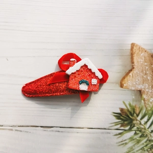 Detail of red glitter Christmas house hair clip on white wooden background with pine branch