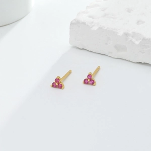 Macro detail of S925 silver triangle stud earrings with red cluster gemstones