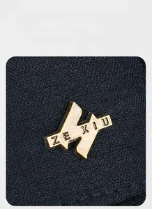 Detailed macro view of vintage gold metal logo on dark blue twill fabric hat texture