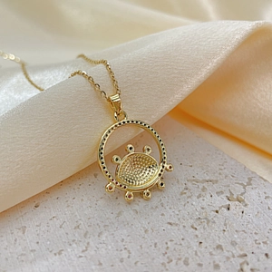Macro shot of gold Evil Eye pendant with multicolored crystals on white stone base