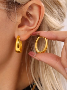 Detail of model wearing polished gold oval hoop earrings showing size and glossy texture