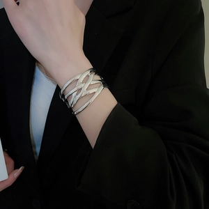 Detail of silver irregular hollow cuff bracelet worn over a black blazer sleeve
