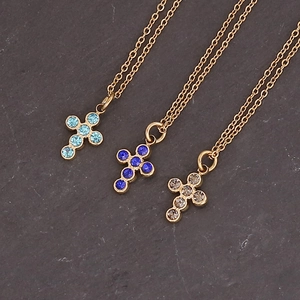 Sunflower cross necklaces in blue and clear crystals on a grey stone background