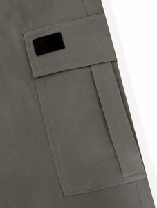 Detail of dark grey cargo pants featuring a large side bellows pocket and cotton twill texture