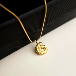 Detailed view of gold nautilus shell pendant on 18K plated stainless steel necklace