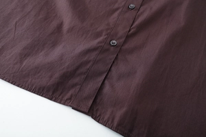 Macro view of dark brown cotton poplin shirt showing placket buttons and sewing details