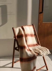 Detail of soft cream and brown striped scarf with tassels on a wooden chair