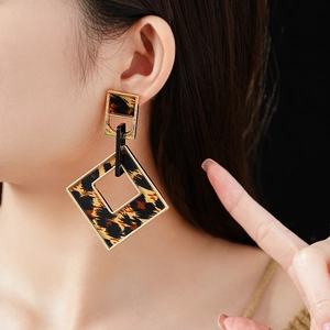 Close-up of geometric leopard print earrings with metallic frames on a model