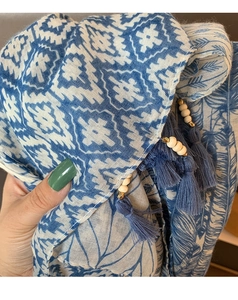 Detailed view of blue and white geometric scarf fabric with wooden beads and blue tassels