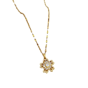 Collier en acier titane doré avec pendentif fleur serti de zircons sur fond blanc