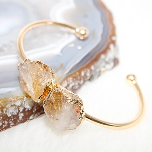 Macro shot of gold-plated open cuff bracelet featuring dual natural citrine raw stones