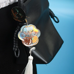 Detail showing colorful acrylic cloud pendant with white silk tassel on a black leather bag