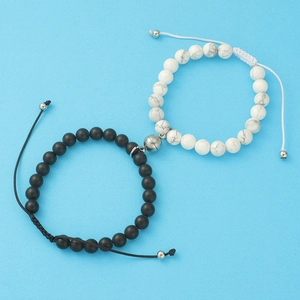 Magnetic couple bracelets with black matte agate and white turquoise beads on blue background