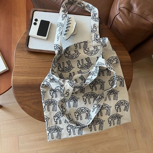 Detail of canvas tote bag featuring repeated black sheep print on a beige surface